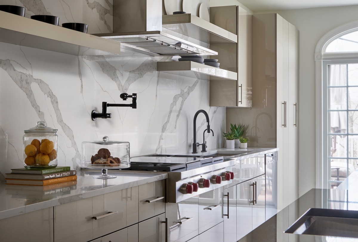 For maximum effect, designer Garcia ran the Statuario Nuvo quartz by Caesarstone all the way up the wall behind the Wolf stove. The high-glass champagne cabinets effortlessly reflect light. 