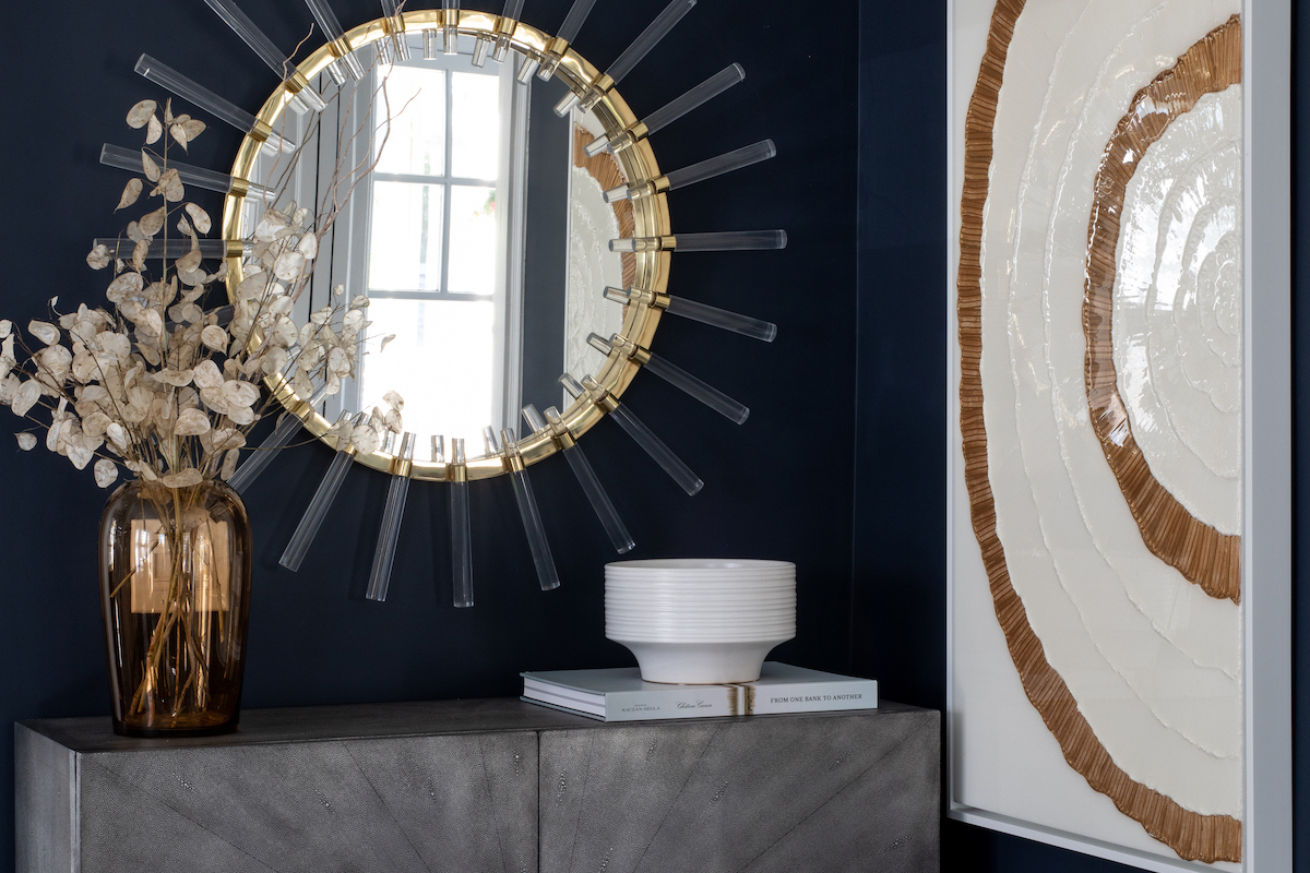 Cloe mirror from John Richard and “Elegant Blooming” art, available through Karen B. Wolf Interiors. On the walls, Benjamin Moore’s Hale Navy lets the gold touches pop. 