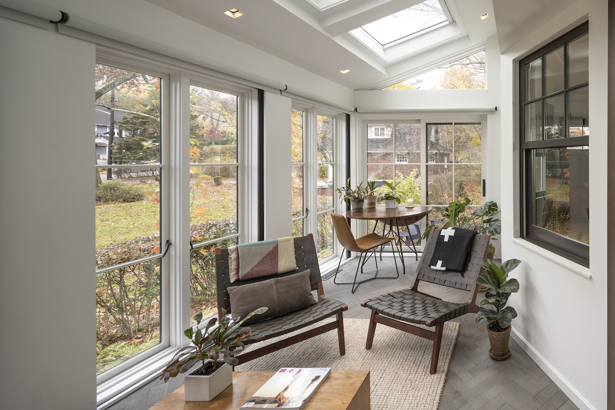 : A skylight and a series of floor-to-ceiling windows and doors allow light to flow freely into the sunroom, nourishing the home’s inhabitants and their collection of houseplants. The gray basalt floor tiles echo the bluestone terrace in the backyard.