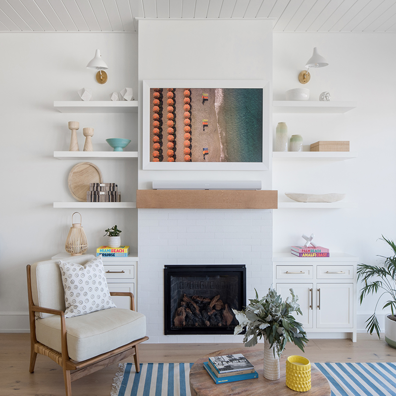 Around the gas fireplace, the designer used glazed brick tiles that show organic imperfections. The “floating” wood shelves contribute to the room’s airy flow, while the matching credenzas provide out-of-sight storage and the Frame TV cleverly camouflages electronic distractions.