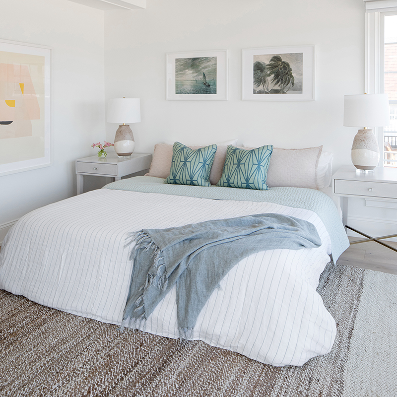 The laid-back design of this primary bedroom offers the perfect place to crash after a day spent chasing waves—or kids—or both. The designer refreshed the original ceiling’s wood frames in Benjamin Moore’s Simply White and incorporated choice decorative touches such as the Jaipur Living area rug, custom accent pillows and vintage art over the Universal Furniture bed.