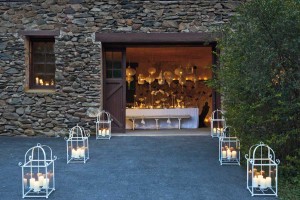 The stone facade keeps the carriage house cool even on warm summer nights, while foot lanterns guide visitors to the entrance. A peek inside shows a ceiling hung with Moroccan lanterns and a table glowing with candlelight.