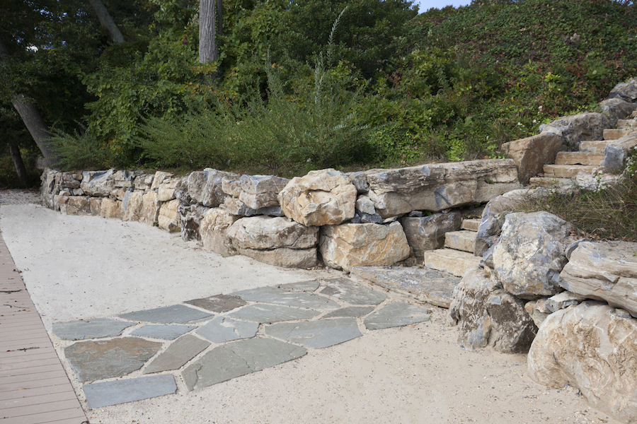 Unlike landscaping, which uses plants and flowers, hardscaping incorporates materials such as stone, brick, wood, iron and concrete to sculpt stylish outdoor living areas. This page: A wall of boulders and a slate pathway make a beachy statement.