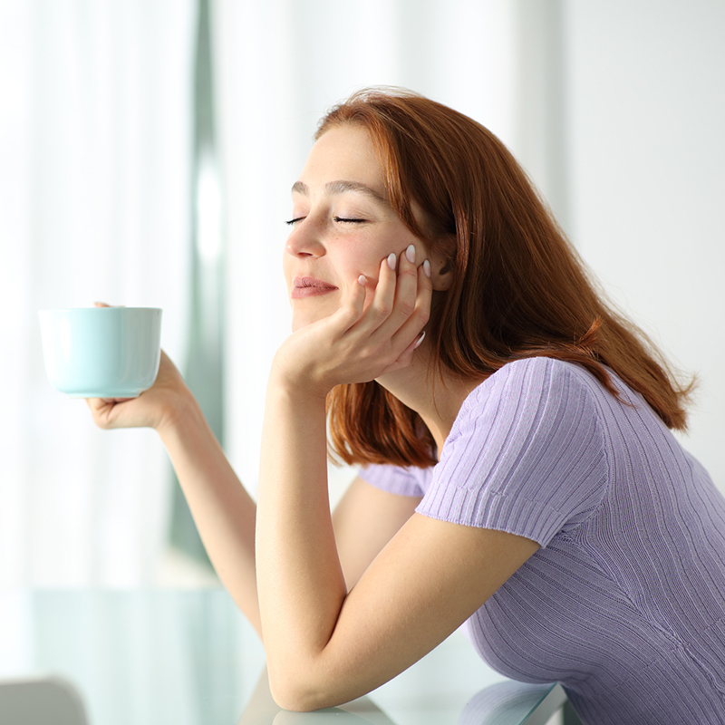 Happy woman holding coffee cup resting in apartment