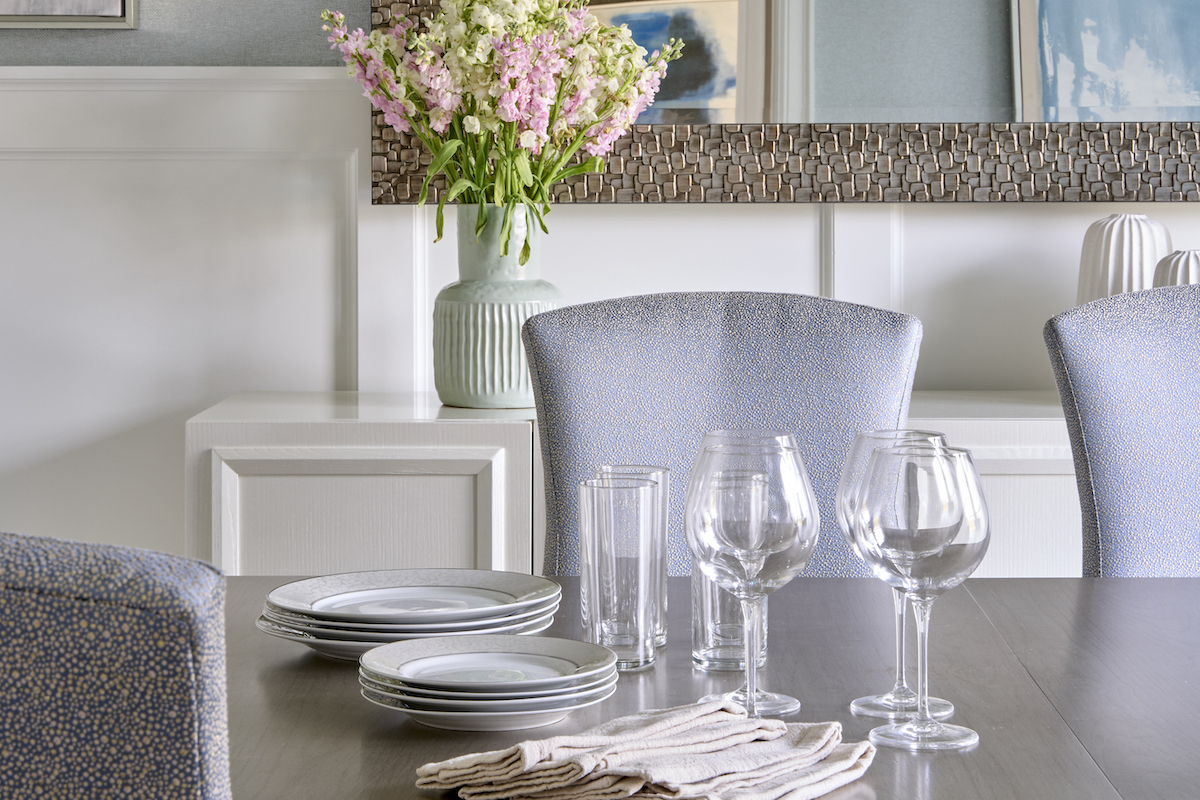 Though there are sparks of glam throughout the space, the dining room is where it rules, in the gilt mirror from Uttermost, the Arteriors chandelier of polished nickel and glass, the blue Bernhardt chairs that offer a subtle sparkle and the Vanguard buffet with its white shimmer-painted finish. The wallpaper from York Wallcovering adds a subtle contrast to the bright white wainscoting.
