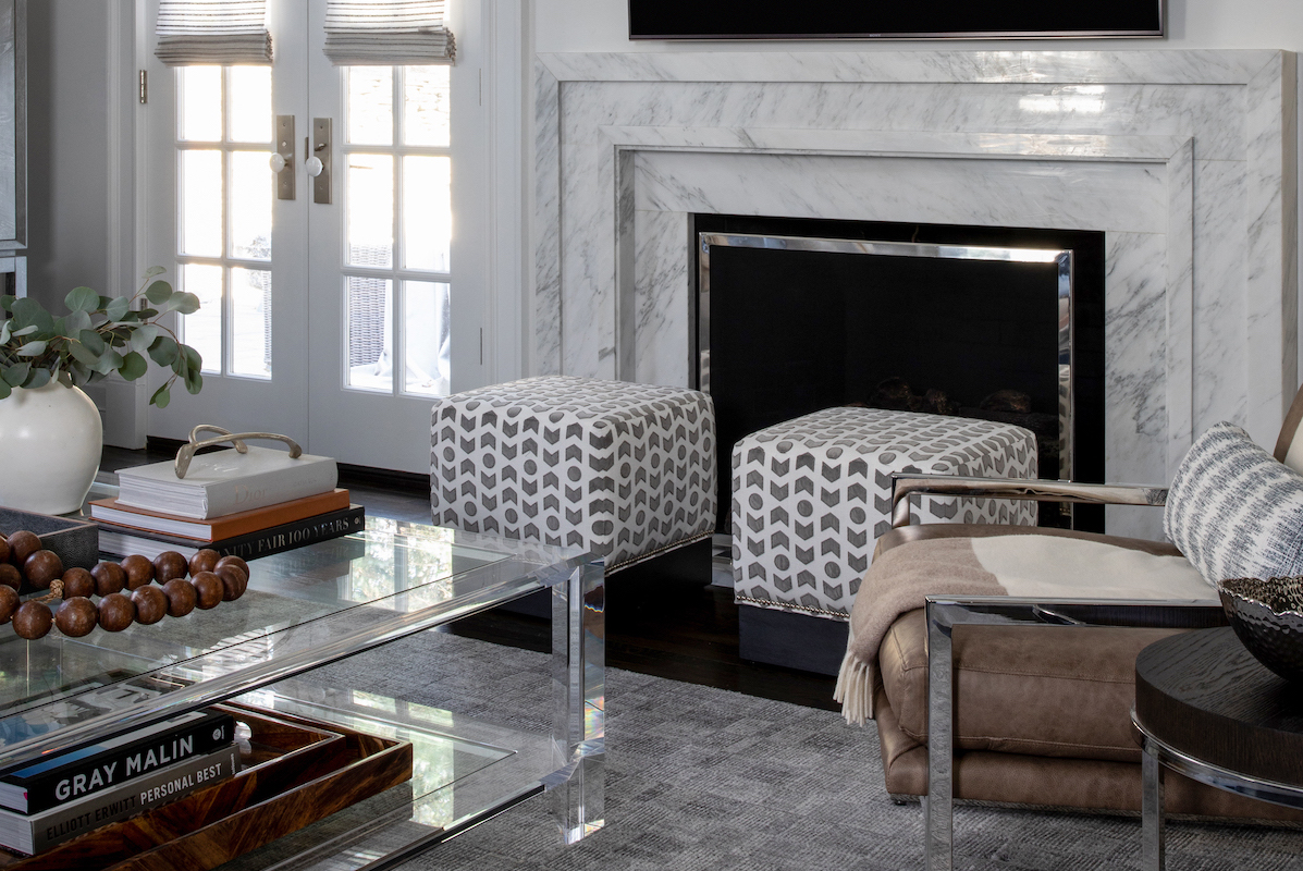 Contributing to the relaxed luxe vibe, the custom fabric-upholstered ottomans complement the custom statuary marble fireplace.