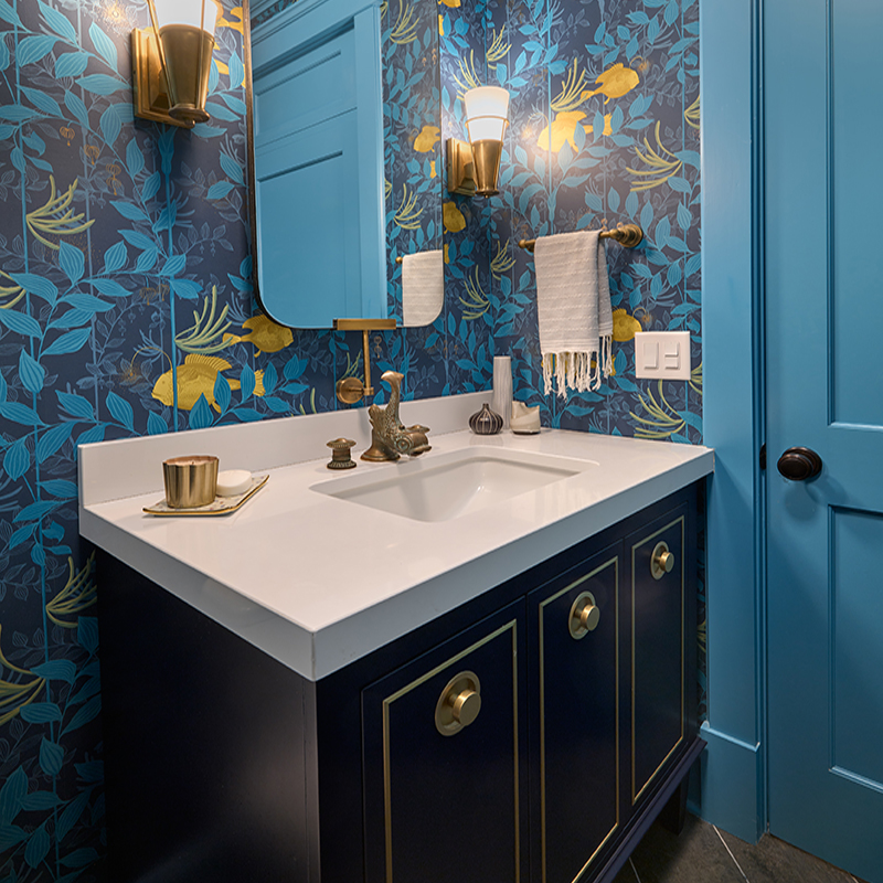 The Grecian-style dolphin faucet spout inspired this powder room’s tropical wallcovering by Lee Jofa.