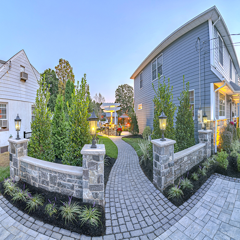 The cobblestone walkway wraps around from the driveway in the front to the backyard; cobblestone-style hardscaping contrasts nicely with the more modern ledgestone pavers.
